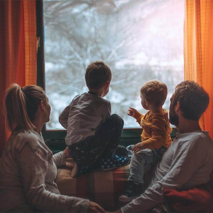 A family of four look outside a window.